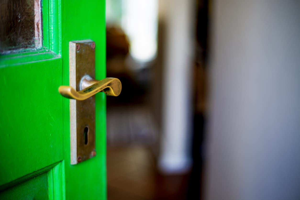 Green door open ajar onto entrance hall